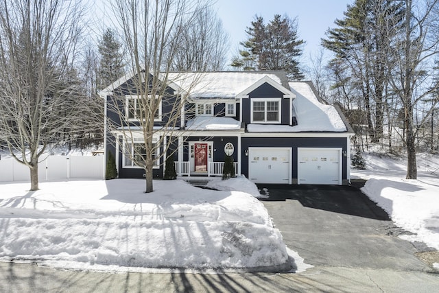 traditional home with aphalt driveway, a porch, and fence