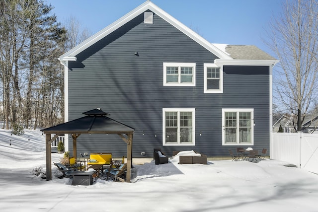 snow covered house featuring a gazebo and fence