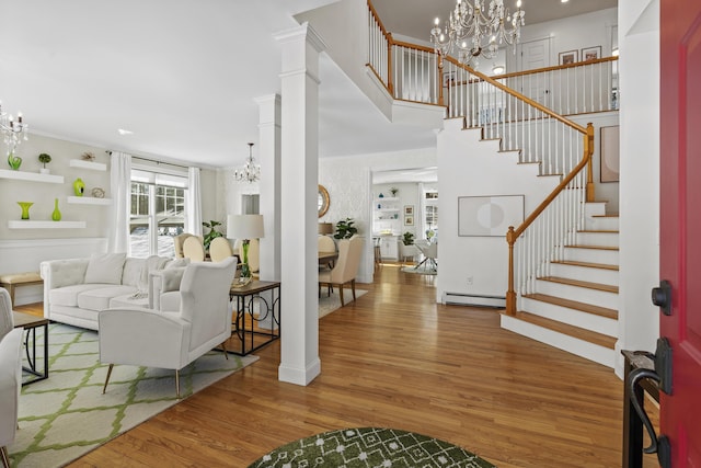 entrance foyer featuring a notable chandelier, wood finished floors, a baseboard radiator, stairs, and ornate columns