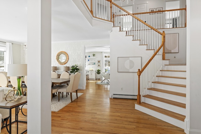 entryway featuring stairs, ornamental molding, a high ceiling, wood finished floors, and a baseboard radiator