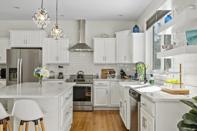 kitchen with light wood finished floors, plenty of natural light, appliances with stainless steel finishes, and wall chimney exhaust hood