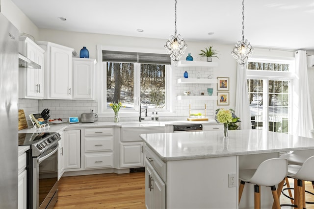 kitchen featuring a center island, a breakfast bar, stainless steel electric range, white cabinets, and a sink