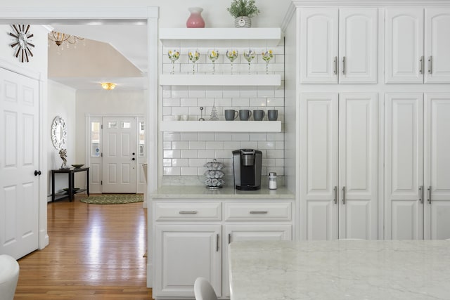 kitchen with tasteful backsplash, light stone countertops, wood finished floors, white cabinets, and open shelves