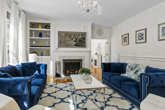 living area featuring wallpapered walls, a glass covered fireplace, wood finished floors, and a wainscoted wall