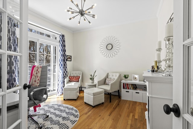 living area with an inviting chandelier, light wood-style flooring, a wealth of natural light, and ornamental molding