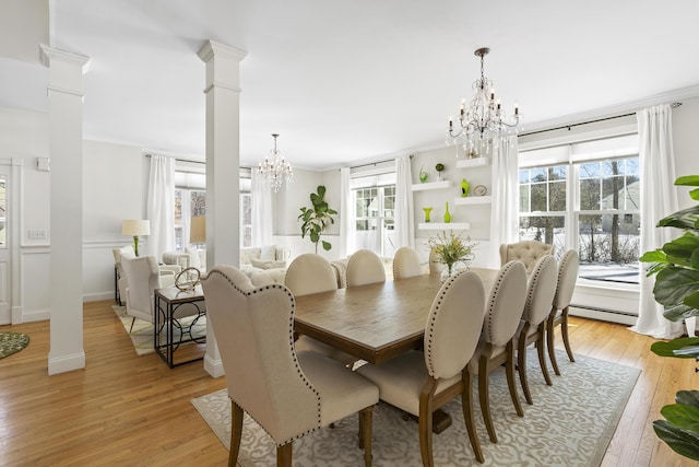 dining room with crown molding, light wood-style floors, a notable chandelier, ornate columns, and a baseboard radiator