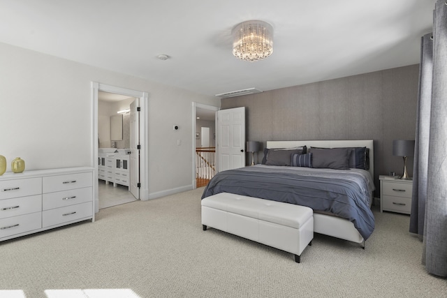 bedroom featuring baseboards, ensuite bathroom, and light carpet