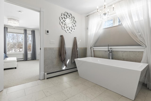 interior space featuring a freestanding tub, a baseboard heating unit, and a notable chandelier