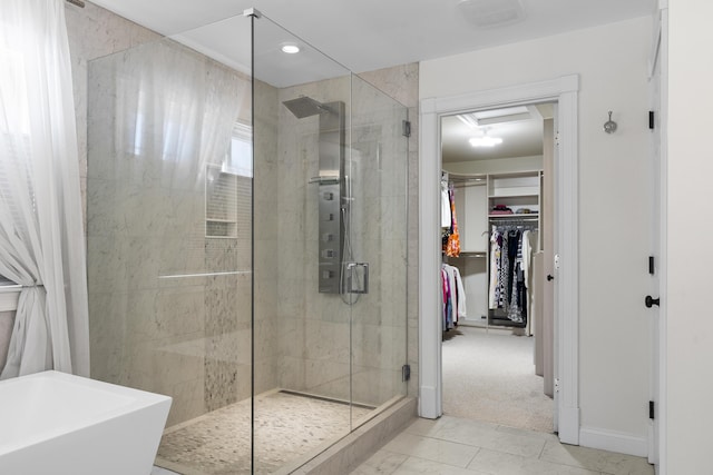 full bathroom with a walk in closet, a soaking tub, and a stall shower