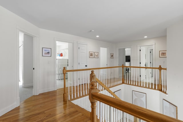 hall featuring an upstairs landing, recessed lighting, washer / dryer, and wood finished floors