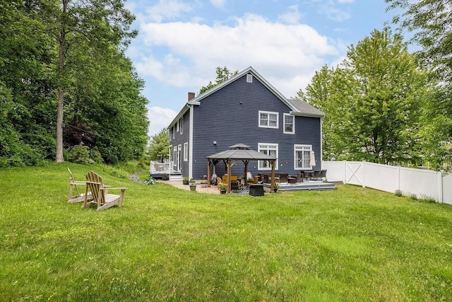 rear view of house with a deck, a gazebo, fence, and a lawn