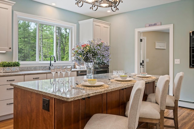 271 Red Gate Ln, Acton, ME 04001 - kitchen with wood finished floors, white cabinets, light stone countertops, a kitchen bar, and a center island