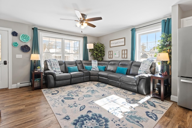 living area featuring baseboards, a baseboard radiator, a ceiling fan, and wood finished floors