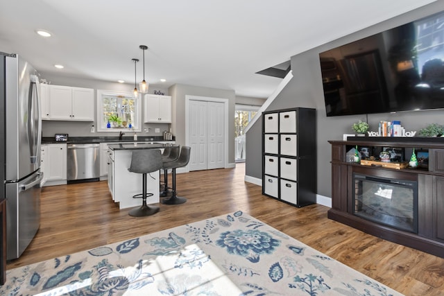 kitchen featuring recessed lighting, dark wood-type flooring, white cabinetry, a kitchen breakfast bar, and appliances with stainless steel finishes