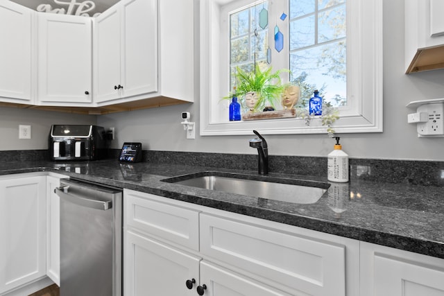 kitchen with dark stone counters, white cabinetry, a sink, and stainless steel dishwasher