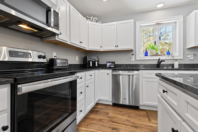 kitchen featuring stainless steel appliances, a sink, and white cabinetry