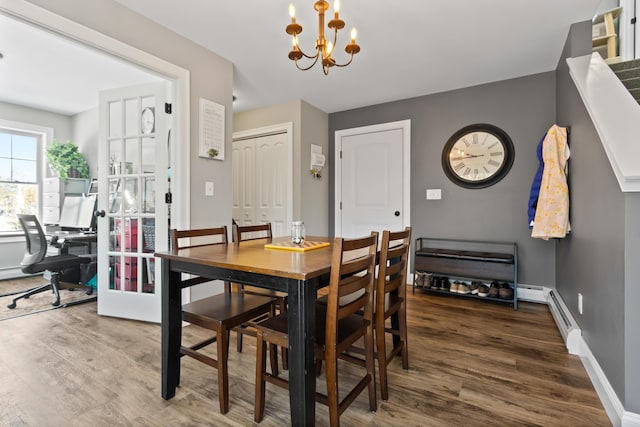 dining room featuring baseboard heating, an inviting chandelier, wood finished floors, and baseboards