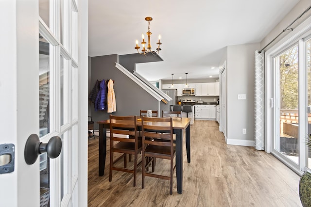 dining area with light wood-style floors, baseboards, and a notable chandelier