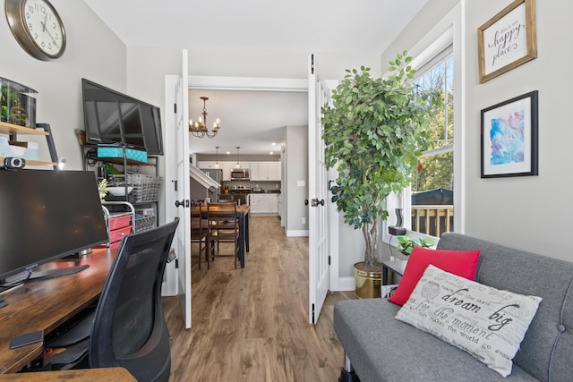 office space featuring baseboards, a chandelier, and wood finished floors