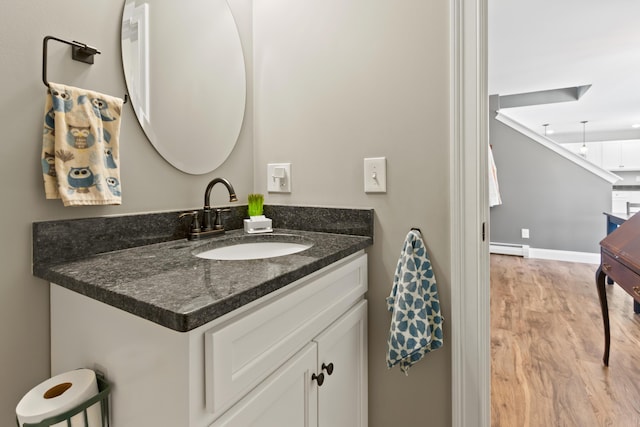 bathroom featuring baseboards, a baseboard heating unit, wood finished floors, and vanity