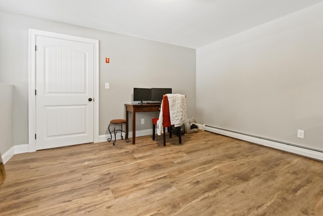 office area with a baseboard heating unit, light wood-style flooring, and baseboards