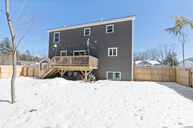 snow covered house featuring a fenced backyard, a wooden deck, and stairs