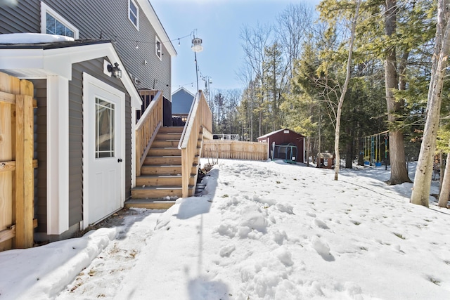 yard layered in snow featuring an outbuilding, fence, and stairway