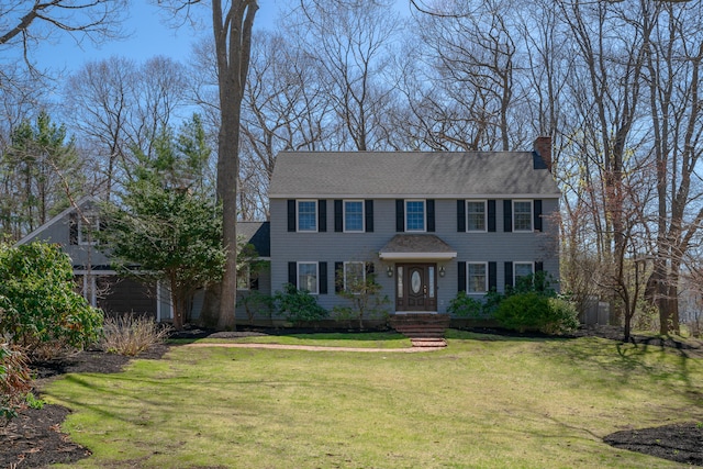 colonial home featuring a chimney and a front lawn