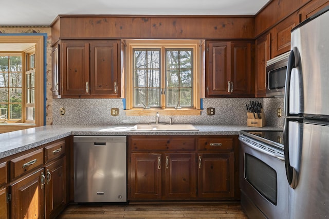kitchen featuring dark wood-style floors, light countertops, a sink, backsplash, and stainless steel appliances