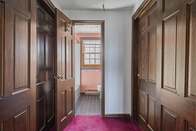 corridor featuring baseboards and dark colored carpet