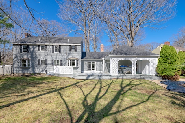 rear view of property with a lawn, a chimney, and a deck