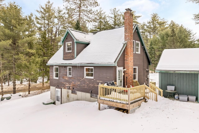 snow covered property featuring a chimney and a wooden deck