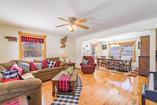 living room with a baseboard heating unit, hardwood / wood-style floors, and ceiling fan with notable chandelier