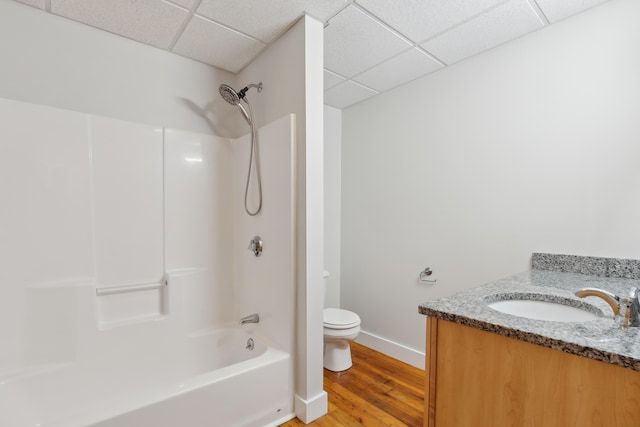 bathroom featuring toilet,  shower combination, a paneled ceiling, and wood finished floors