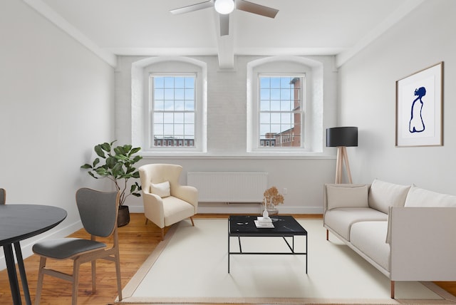 living area featuring plenty of natural light, radiator heating unit, baseboards, and wood finished floors