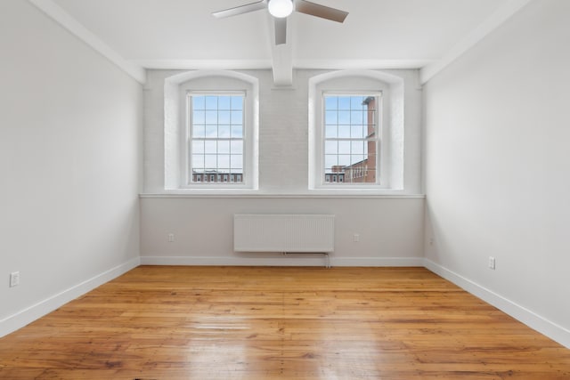 unfurnished room with baseboards, ceiling fan, wood finished floors, and radiator