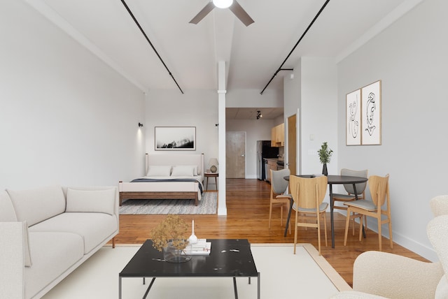 living room featuring ceiling fan, baseboards, and wood finished floors