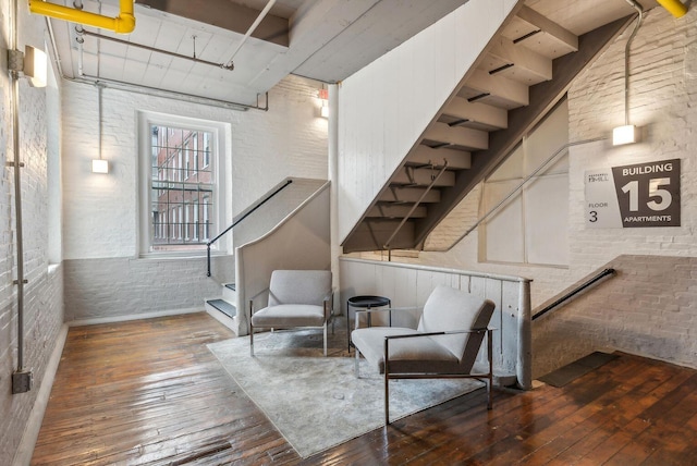 living area featuring hardwood / wood-style flooring and brick wall