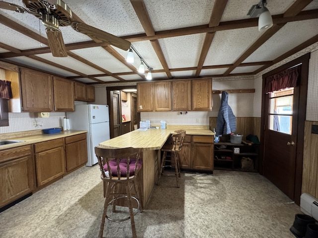 143 Main St, Sangerville, ME 04479 - kitchen featuring freestanding refrigerator, brown cabinetry, coffered ceiling, a breakfast bar area, and a peninsula