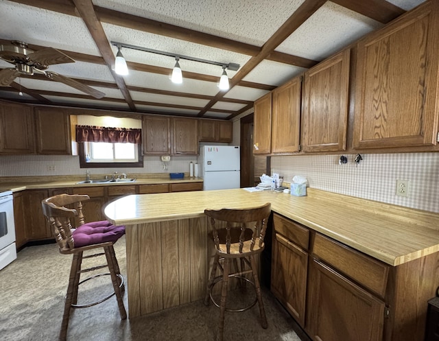 143 Main St, Sangerville, ME 04479 - kitchen featuring white appliances, a sink, light countertops, and a breakfast bar area