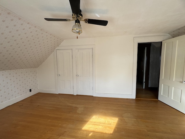 143 Main St, Sangerville, ME 04479 - unfurnished bedroom with wood finished floors, baseboards, wallpapered walls, lofted ceiling, and a ceiling fan