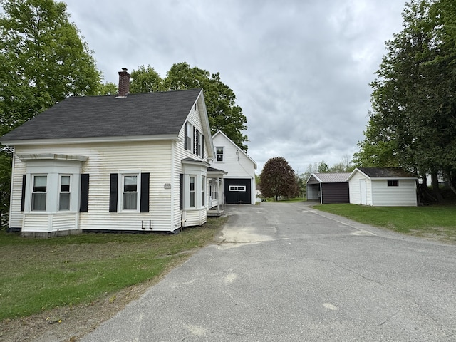 143 Main St, Sangerville, ME 04479 - view of front of house featuring asphalt driveway, a chimney, a front yard, roof with shingles, and a garage