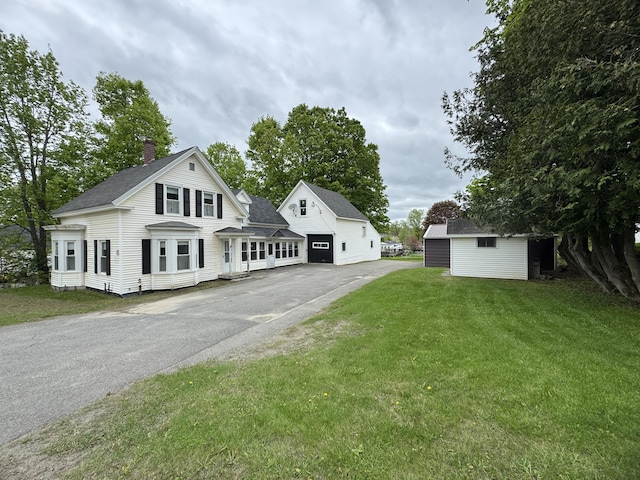 143 Main St, Sangerville, ME 04479 - view of front of property featuring a chimney, asphalt driveway, a front yard, a shingled roof, and an outdoor structure