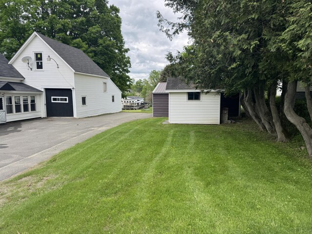 143 Main St, Sangerville, ME 04479 - view of green lawn featuring a garage, an outdoor structure, and asphalt driveway