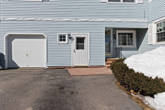 entrance to property featuring a garage and aphalt driveway