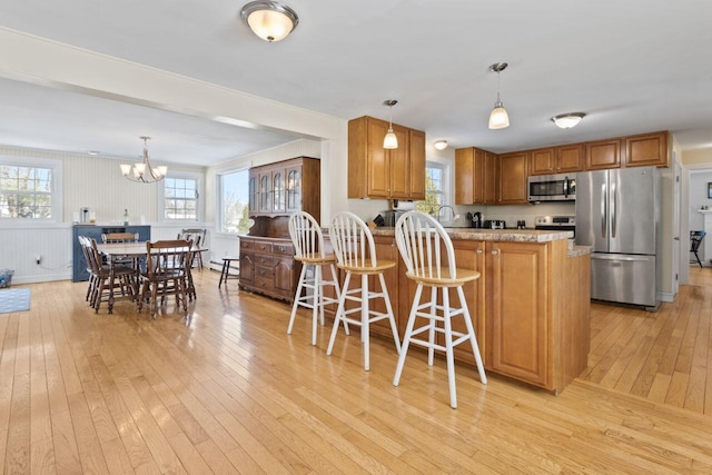 kitchen with brown cabinetry, stainless steel appliances, and light wood-style floors