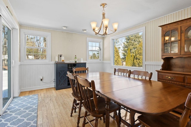 dining room featuring a notable chandelier, wainscoting, and light wood-type flooring