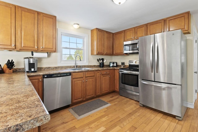 kitchen with a sink, light wood-style floors, brown cabinets, and stainless steel appliances