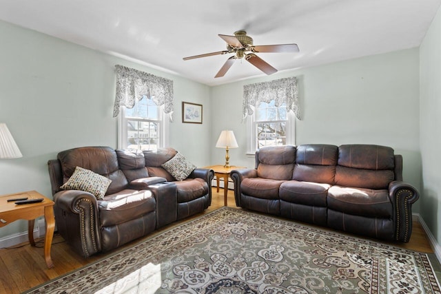 living room with baseboard heating, baseboards, ceiling fan, and wood finished floors