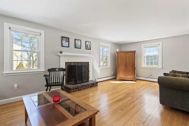 living area with a fireplace, light wood-type flooring, a baseboard heating unit, and baseboards